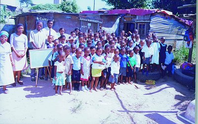 Constance Hadebe with some of the kids who flock to her house in New Dunbar Road in search of education.
